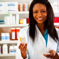 a pharmacy technician holding a medicine bottle with medicine on the shelves behind her