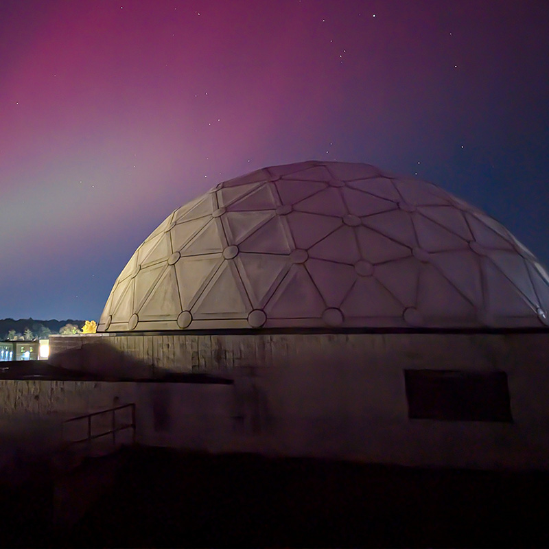 planetarium in the foreground with a blue and magenta night sky and stars in the background